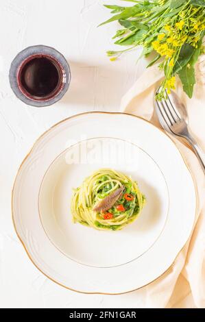 Typisches Italina-Gericht: Spaghetti mit Brokkoli, Sardellen und rotem Pfeffer. Weißer Hintergrund und frische Brokkoli Blumen auf dem Rücken. Stockfoto