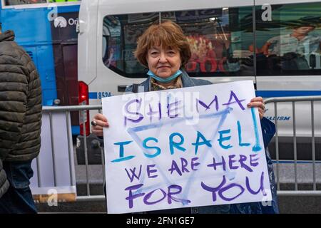 Eine Frau hält ein Plakat mit der Aufschrift "hema Israel we are here for you", als sich der israelisch-amerikanische Rat (IAC) und andere amerikanisch-jüdische Gruppen in Solidarität mit Israel auf dem Times Square versammeln.Tausende von pro-israelischen New Yorkern versammelten sich heute Abend zu einer Kundgebung in Solidarität mit dem Times Square Jüdischer Staat inmitten von Tagen des Raketenfeuers aus Gaza. Die Kundgebung wurde vom Israel American Council zusammengestellt, der ähnliche Demonstrationen in Boston, Los Angeles, Atlanta, Austin, Cleveland, Denver, Houston, Irvine, Las Vegas, Orlando, Philadelphia, Redwood City, Seattle, Scottsdale, Stockfoto