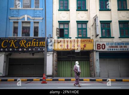 Kuala Lumpur, Malaysia. Mai 2021. Eine muslimische Frau, die als Vorsichtsmaßnahme gegen die Ausbreitung des Coronavirus (Covid-19) eine Gesichtsmaske trägt, geht am ersten Tag der Hari Raya-Feierlichkeiten an den geschlossenen Geschäften in einer leeren Straße vorbei. Der malaysische Premierminister Muhyiddin Yassin hat angekündigt, dass ganz Malaysia aufgrund der zunehmenden Covid-19-Infektionen vom 12. Mai bis 7. Juni 2021 unter den Movement Control Order (MCO) gestellt wird. (Foto von Wong Fok Loy/SOPA Images/Sipa USA) Quelle: SIPA USA/Alamy Live News Stockfoto