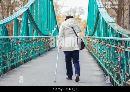 Ältere Frau mit einem Stock in der Hand, der die überquert Grüne Brücke in der Stadt Stockfoto