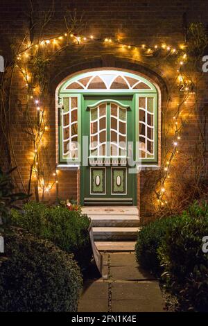Eingangstür des friesischen Hauses, das von Weihnachtslichtern im Dorf Toftum auf der Insel Föhr / Föhr, Nordfriesland, Schleswig-Holstein, Deutschland, beleuchtet wird Stockfoto