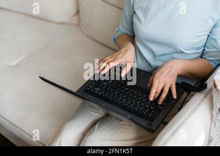 Laptop schwarz ist auf dem Schoß der Frau und sie Tippt mit ihren Händen auf der Tastatur Stockfoto