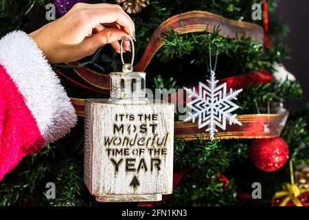 Hände mit Weihnachtsschmuck vor dem Weihnachtsbaum. Stockfoto