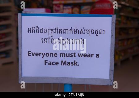 Während eines Ausbruchs von COVID - 19 zeigt ein Supermarkt während der Coronavirus-Pandemie ein zweisprachiges Schild „jeder muss eine Gesichtsmaske tragen“. Phnom Penh, Kambodscha. März 2020. © Kraig Lieb Stockfoto