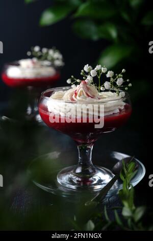 Himbeer-Erdbeer-Dessert mit Käsecreme in verrin auf einem schwarzen Hintergrund Stockfoto