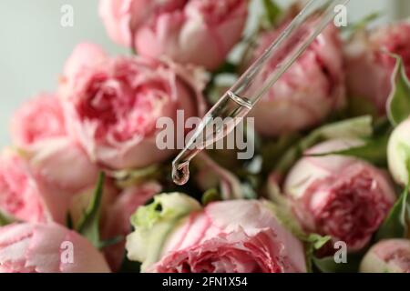 Ätherisches Rosenöl, das aus dem Glasbehälter fällt Stockfoto