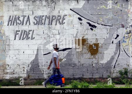 Valencia, Carabobo, Venezuela. Mai 2021. 11.Mai 2021. 11.Mai 2021. Ein Mann, der eine Gesichtsmaske trägt, geht vor ein Graffiti, wo der verstorbene Präsident Kubas und Führer der Revolution in Amerika, Fidel Castro, mit einer Botschaft auf Spanisch erscheint, die sagt: "Lebt wohl Fidel", im Eingangssektor des Staates Naguanagua.Carabobo. Foto: Juan Carlos Hernandez Kredit: Juan Carlos Hernandez/ZUMA Wire/Alamy Live News Stockfoto