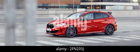 Roter BMW M135i auf dem Parkplatz vor den Bürogebäuden. Modell F40, Baujahr 2019. 306 ps Motor, Beschleunigung 0-100 km / h: 4.8 s. Kat Stockfoto