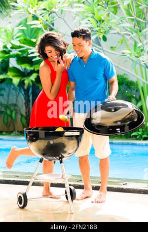 Asiatische hübsches Paar, Grillparty oder Grill draußen am Pool mit gegrillten Maiskolben Stockfoto