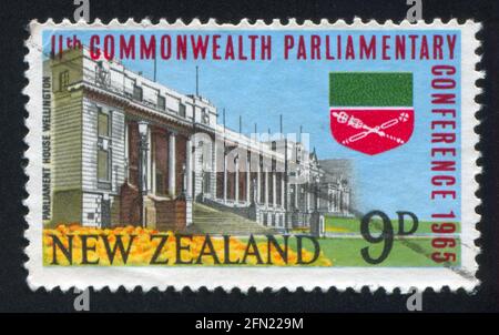 NEUSEELAND - UM 1965: Briefmarke gedruckt von Neuseeland, zeigt Parlamentsgebäude in Wellington und Commonwealth Parliamentary Association Emblem, circa Stockfoto