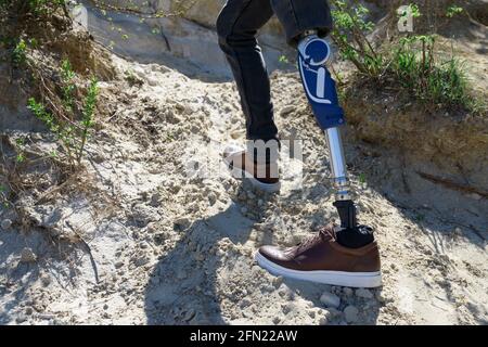 Ein Mann auf einem prothetischen Bein reist durch die Berge. In schwarzen Jeans gekleidet Stockfoto
