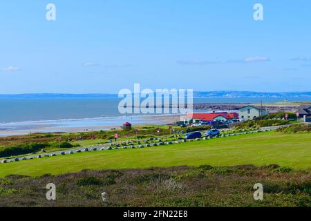 Ein Blick über die gemeinsame Richtung zum beliebten Surfstrand in Rest Bay, Porthcawl.Royal Porthcawl Golf Club Gebäude rechts. Stockfoto