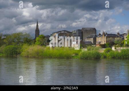 Blick über den Fluss Tweed of Kelso unter einem bedrohlichen Himmel, mit John Hogarth Ltd Kelso Mills und Kelso North Parish Church im Hintergrund. Stockfoto