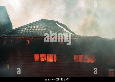 Das Feuer zerstört das Gebäude. Die Feuerwehr gießt Wasser auf das brennende Haus. Menschen ersticken durch den Rauch und Smog des Feuers. Feuer Stockfoto