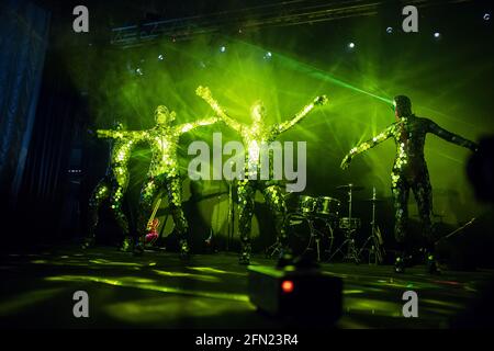 Eine unglaubliche Schönheit der Darbietung von Künstlern und Tänzern auf der Bühne, eine Feuershow mit LED-Anzügen und Lasern, die auf vielen Spiegeldetails in reflektieren Stockfoto