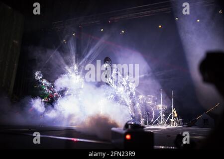 Eine unglaubliche Schönheit der Darbietung von Künstlern und Tänzern auf der Bühne, eine Feuershow mit LED-Anzügen und Lasern, die auf vielen Spiegeldetails in reflektieren Stockfoto