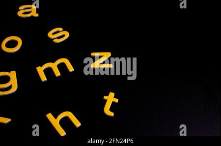 Gelbe, zufällige Buchstaben auf schwarzem Hintergrund mit Kopierfläche Stockfoto