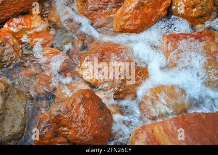 Natürliche Quelle von mineralischem Heilwasser Narzan in der Region Elbrus, Kabardino-Balkarische Republik, Russland. Mineralquelle mit oranger Metallfarbe wat Stockfoto