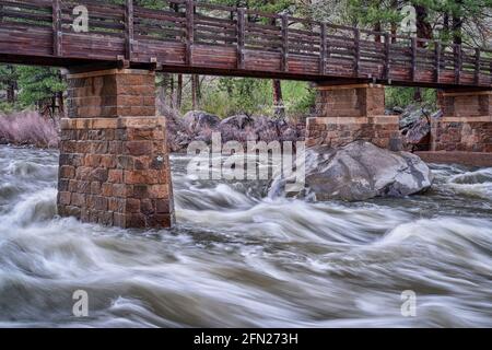 Poudre River unter der Grayrock Trail Brücke in einem Canyon über Fort Collins, Colorado, Regenfrühlingslandschaft mit hohem Fluss Stockfoto