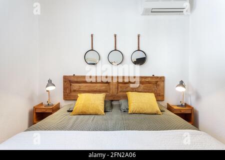 Hotelzimmer mit großem Bett, ein paar Handtüchern und Kopfkissen darauf, Spiegel. Auf jeder Seite befinden sich Nachttische mit Lampen. Stockfoto