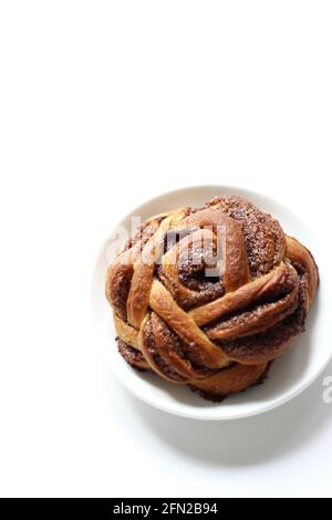Zimt-Brötchen auf Untertasse isoliert auf weißem Hintergrund. Frühstück Dessert. Stockfoto