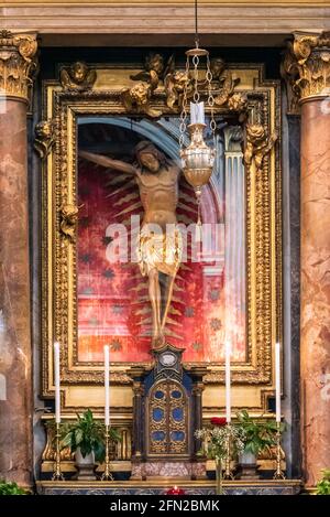 Nahaufnahme eines alten hölzernen Kruzifixes, das hinter einem Glas aufbewahrt wird Die Mauer in der katholischen Kirche in Rom Stockfoto