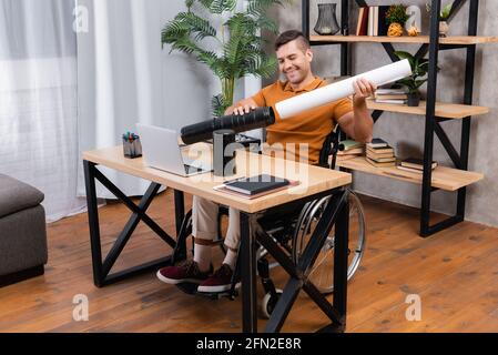 Behinderter Architekt, der Papier während der Arbeit in das Zeichenrohr einlegt Heimbüro Stockfoto