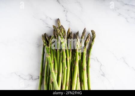 Grüner Spargel isoliert auf weißem Marmorboden. Stockfoto