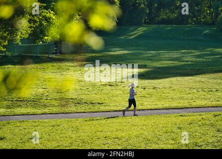 MÜNCHEN, DEUTSCHLAND - 11. Mai 2021: Frau beim Joggen durch den Park in München im Sommer. Konzept für sportliche Aktivitäten während des Lebens in der Stadt Stockfoto