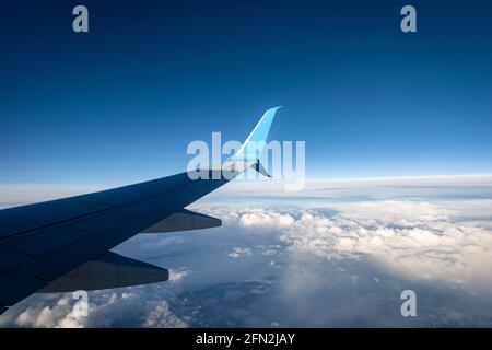 Verkehrsflugzeug während des Fluges über den Wolken und dem klaren blauen Himmel. Blick durch das Flugzeugfenster. Stockfoto