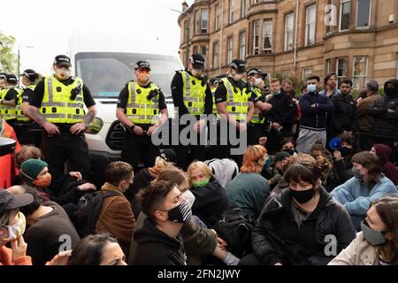 Glasgow, Schottland, Großbritannien. Mai 2021. Demonstranten versammeln sich in Pollokshields, um die Abschiebung von Einzelpersonen aus dem Haushalt zu verhindern. Die starke Polizeipräsenz setzt sich fort, wobei die Polizei und die Demonstranten, die in der Kenmure Street Street sitzen und den Zugang blockieren, angespannt sind. Kredit: Iain Masterton/Alamy Live Nachrichten Stockfoto