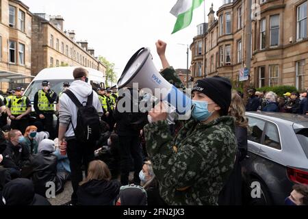 Glasgow, Schottland, Großbritannien. Mai 2021. Demonstranten versammeln sich in Pollokshields, um die Abschiebung von Einzelpersonen aus dem Haushalt zu verhindern. Die starke Polizeipräsenz setzt sich fort, wobei die Polizei und die Demonstranten, die in der Kenmure Street Street sitzen und den Zugang blockieren, angespannt sind. Kredit: Iain Masterton/Alamy Live Nachrichten Stockfoto