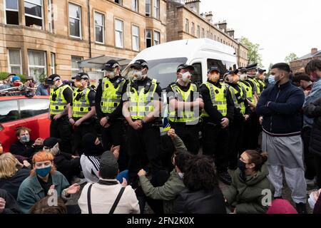 Glasgow, Schottland, Großbritannien. Mai 2021. Demonstranten versammeln sich in Pollokshields, um die Abschiebung von Einzelpersonen aus dem Haushalt zu verhindern. Die starke Polizeipräsenz setzt sich fort, wobei die Polizei und die Demonstranten, die in der Kenmure Street Street sitzen und den Zugang blockieren, angespannt sind. Kredit: Iain Masterton/Alamy Live Nachrichten Stockfoto