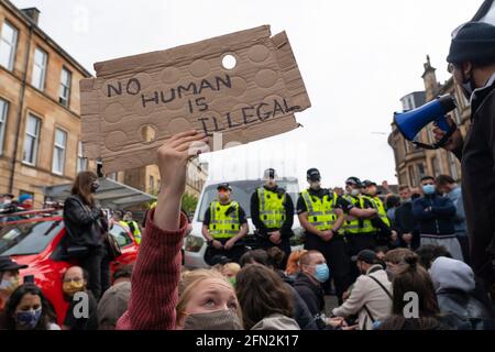 Glasgow, Schottland, Großbritannien. Mai 2021. Demonstranten versammeln sich in Pollokshields, um die Abschiebung von Einzelpersonen aus dem Haushalt zu verhindern. Die starke Polizeipräsenz setzt sich fort, wobei die Polizei und die Demonstranten, die in der Kenmure Street Street sitzen und den Zugang blockieren, angespannt sind. Kredit: Iain Masterton/Alamy Live Nachrichten Stockfoto