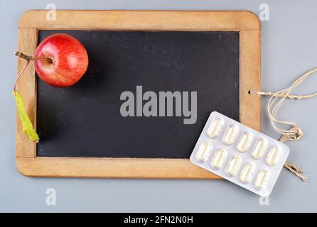 Kreidetafel isoliert auf grau mit Pillen und einem roten Apfel Stockfoto