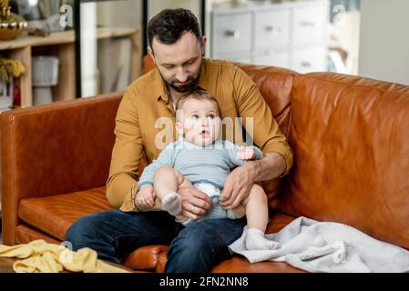 Vater wechselt die Windel zu seinem kleinen Sohn allein zu Hause. Babysitter Vater und schwierige Elternschaft. Stockfoto