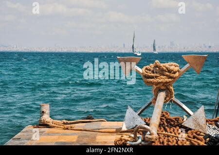 Ein großer Anker auf dem Dock mit rostigen Ketten, schöne Boote Und Meereslandschaft im Hintergrund Stockfoto