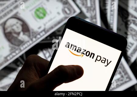 In dieser Abbildung sehen Sie das amerikanische Online-Zahlungsplattform Amazon Pay, das auf einem Smartphone mit US-Dollar (USD) im Hintergrund zu sehen ist. Stockfoto