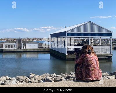 DER FOTOGRAF SITZT AM PIER UND FOTOGRAFIERT VÖGEL MIT LANGER LINSE WÄHREND DER COVID-19-PANDEMIE. Stockfoto