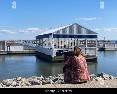 DER FOTOGRAF SITZT AM PIER UND FOTOGRAFIERT VÖGEL MIT LANGER LINSE WÄHREND DER COVID-19-PANDEMIE. Stockfoto