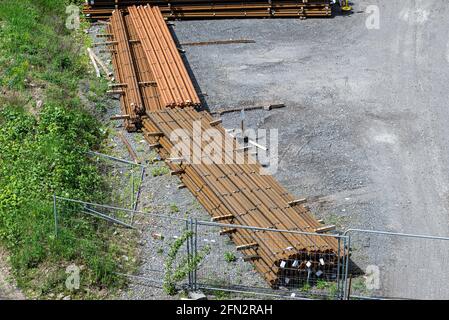 Lange und dicke, rostbedeckte Stahlstäbe, die von oben auf einem Kiesquadrat gestapelt wurden. Stockfoto