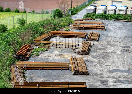 Lange und dicke, rostbedeckte Stahlstäbe, die von oben auf einem Kiesquadrat gestapelt wurden. Stockfoto