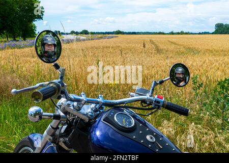 Mann mit Bart und Brille spiegelt sich im Spiegel eines Motorrades Stockfoto