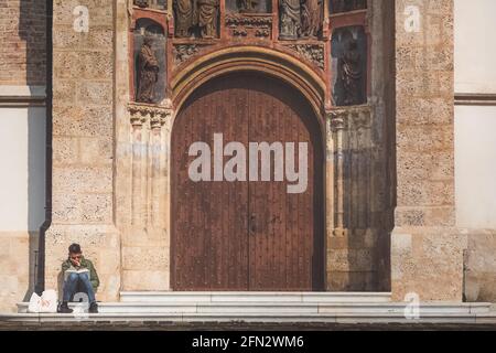 Zagreb, Kroatien - 7 2018. Oktober: Ein Mann macht eine Pause und liest ein Buch über die Stufen der großen gotischen Tür und den Eingang zur Kirche des heiligen Markus in ol Stockfoto