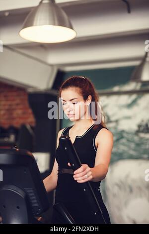 junge Fitness Frau führen Übung Übung-Maschine im Fitness-Studio Stockfoto