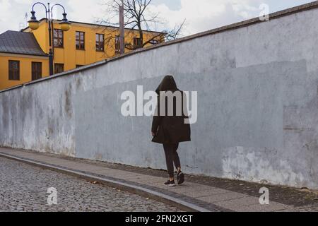 Mann in einer schwarzen Kapuzenjacke, der auf der Straße unterwegs ist Stockfoto