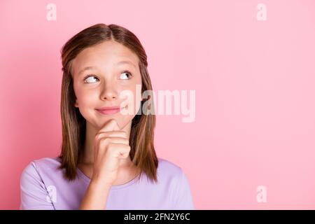 Foto von verträumt schön kleines Mädchen aussehen leeren Raum denken Halten Sie die Hand Kinn Plan isoliert auf rosa Hintergrund Stockfoto