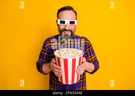 Portrait von attraktiven fröhlichen Kerl in den Händen halten Snack essen Corn watching Video Spaß isoliert über leuchtend gelbe Farbe Hintergrund Stockfoto