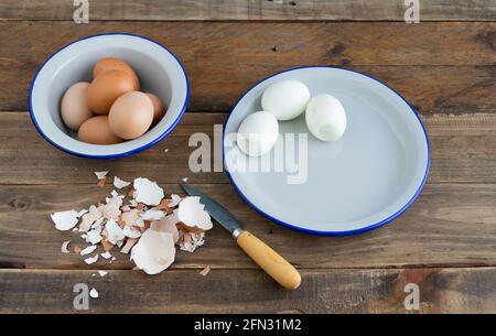 Geschälte gekochte Eier auf einem weißen Teller. Schüssel mit gekochten Eiern. Holzhintergrund. Speicherplatz kopieren. Eierschale. Stockfoto