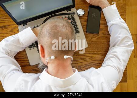 Telemedizin, erschöpfter Arzt nach einem Arbeitstag mit einem Nickerchen auf seinem Laptop Stockfoto